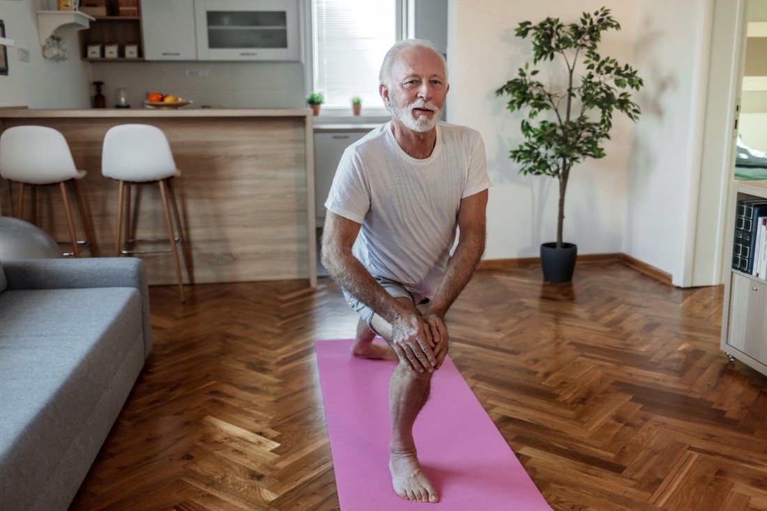 Senior man doing fitness workouts and stretching at home.