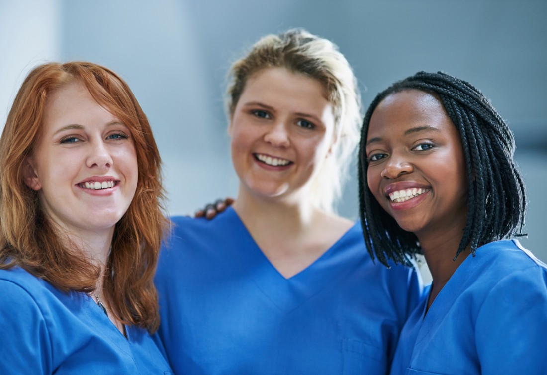 Three young female caregivers smile for the camera