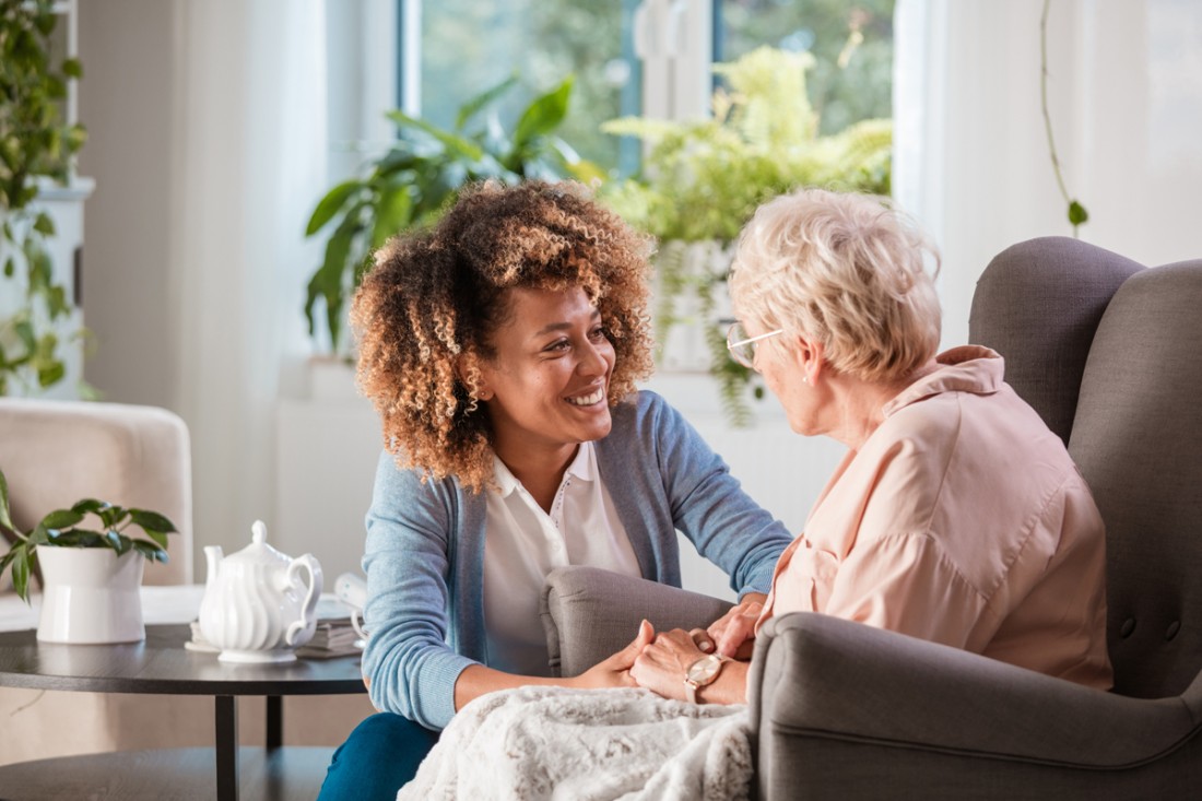 Smiling female caregiver talking with a senior in her home